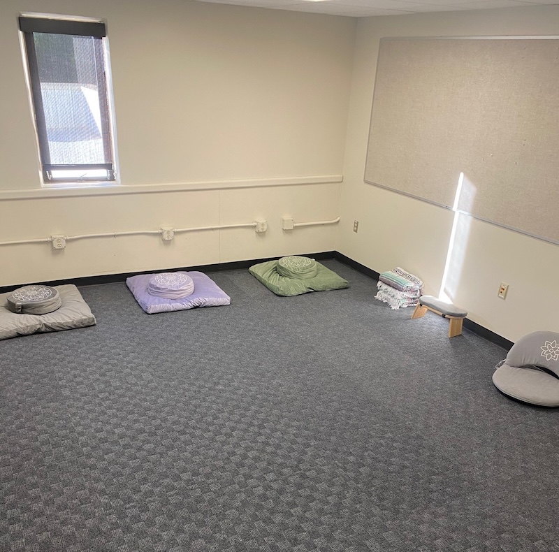 A room with one bright windows and a group of floor pillows